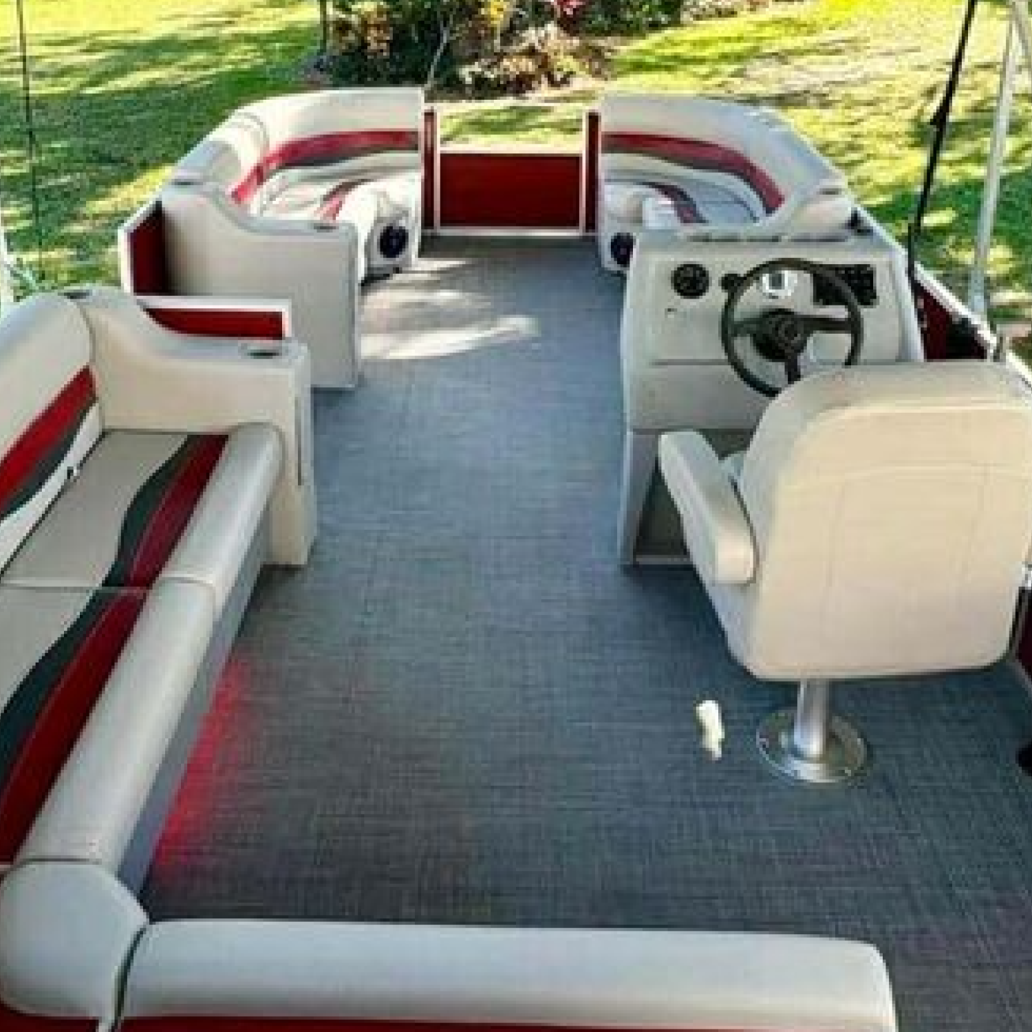Pontoon boat with premium gray, red, and charcoal corner and bench seats with a helm chair