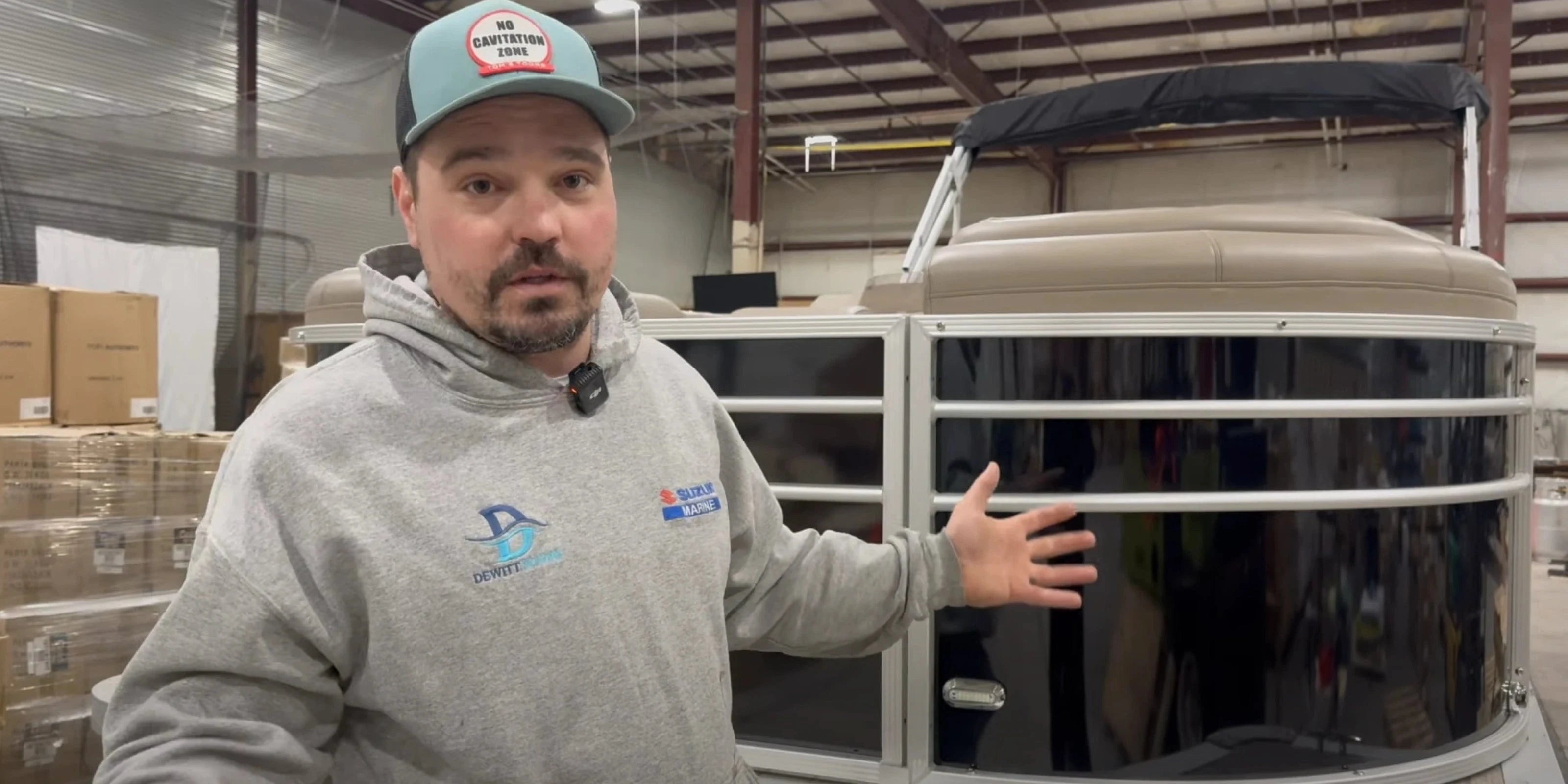 Guy standing in front of a pontoon boat in a warehouse