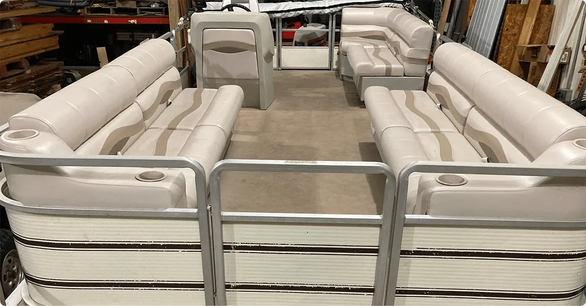 Pontoon boat with premium beige furniture bench seats, corner seats, and a console