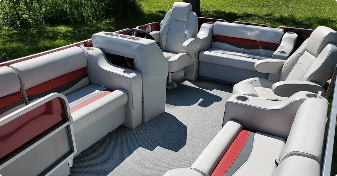Pontoon boat with classic furniture charcoal and red bench seats, arm rests, helm chairs, and a console