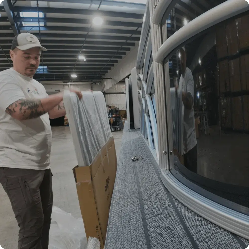 Guy working on a pontoon boat in a warehouse adding fencing