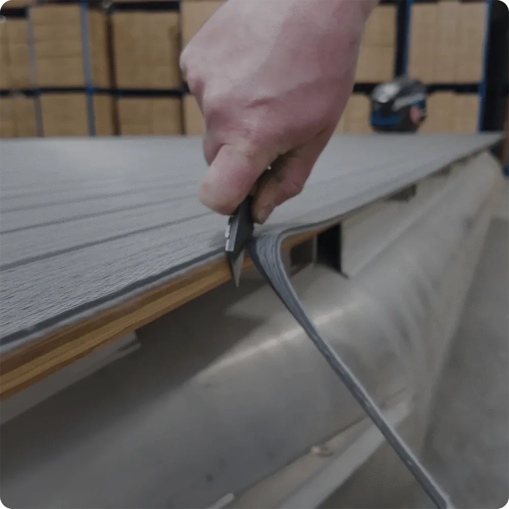 Person cutting vinyl flooring on pontoon boat deck