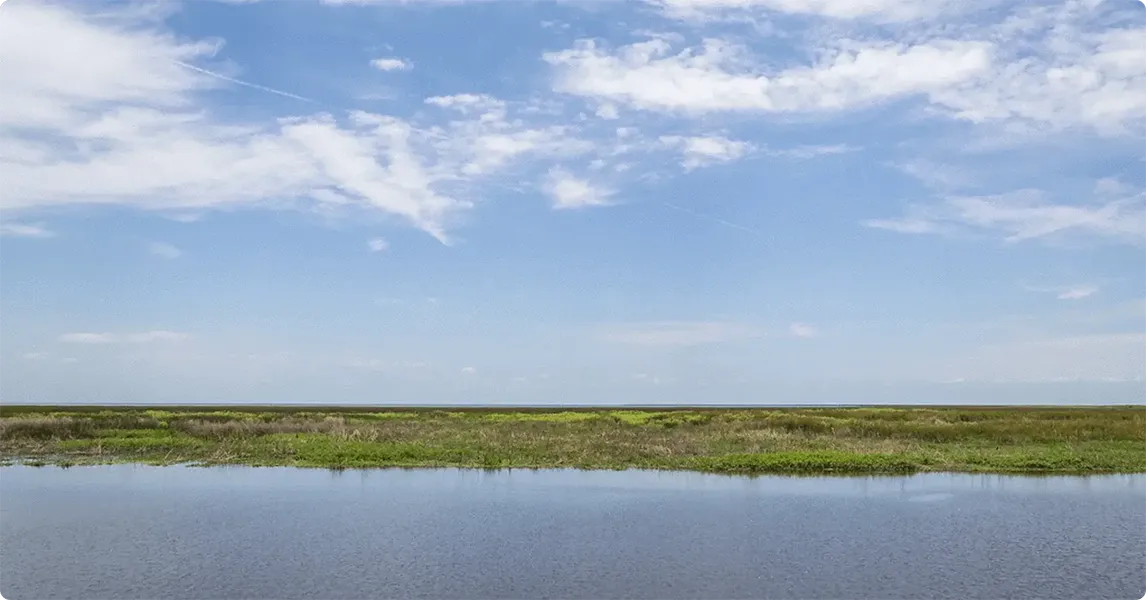 Wide-open landscape with water body and blue sky