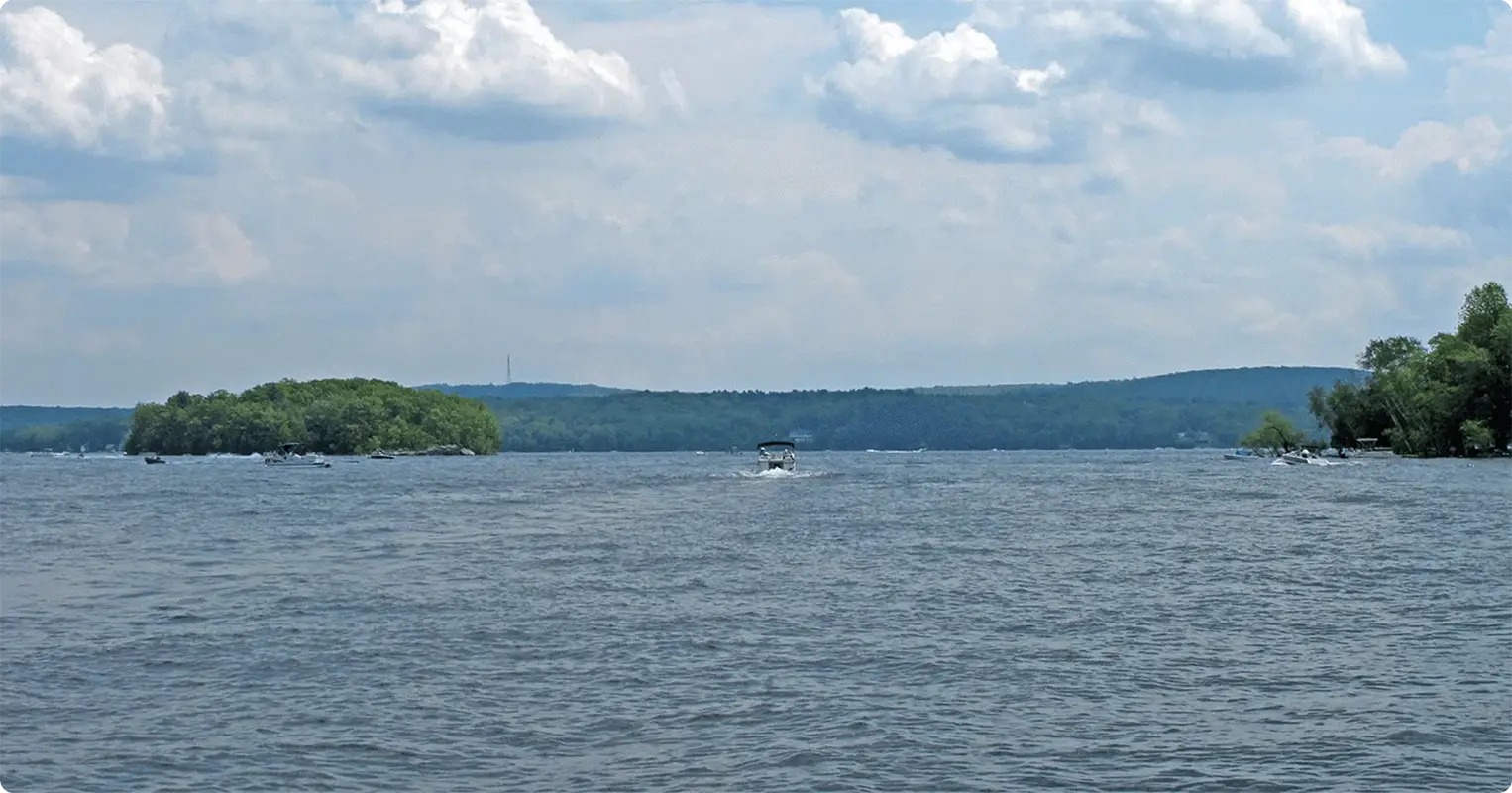 Lake scene with a boat in the distance under a partly cloudy sky.