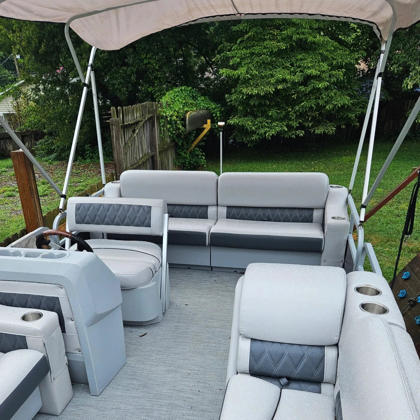 Pontoon boat with luxury furniture including bench seats, cupholders, lean backs, flip flops, console, and a Bimini top