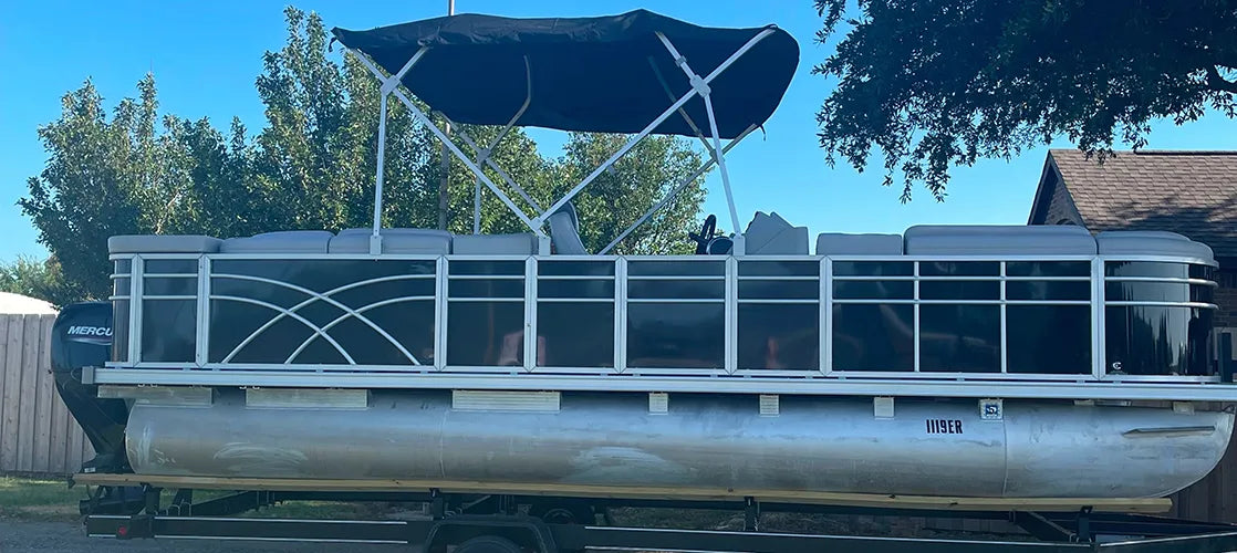 Pontoon boat with black fence with sun deck and a bimini top