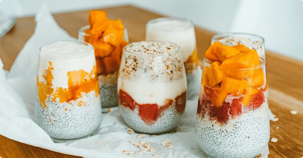 Small glasses filled with a layered dessert on a wooden surface